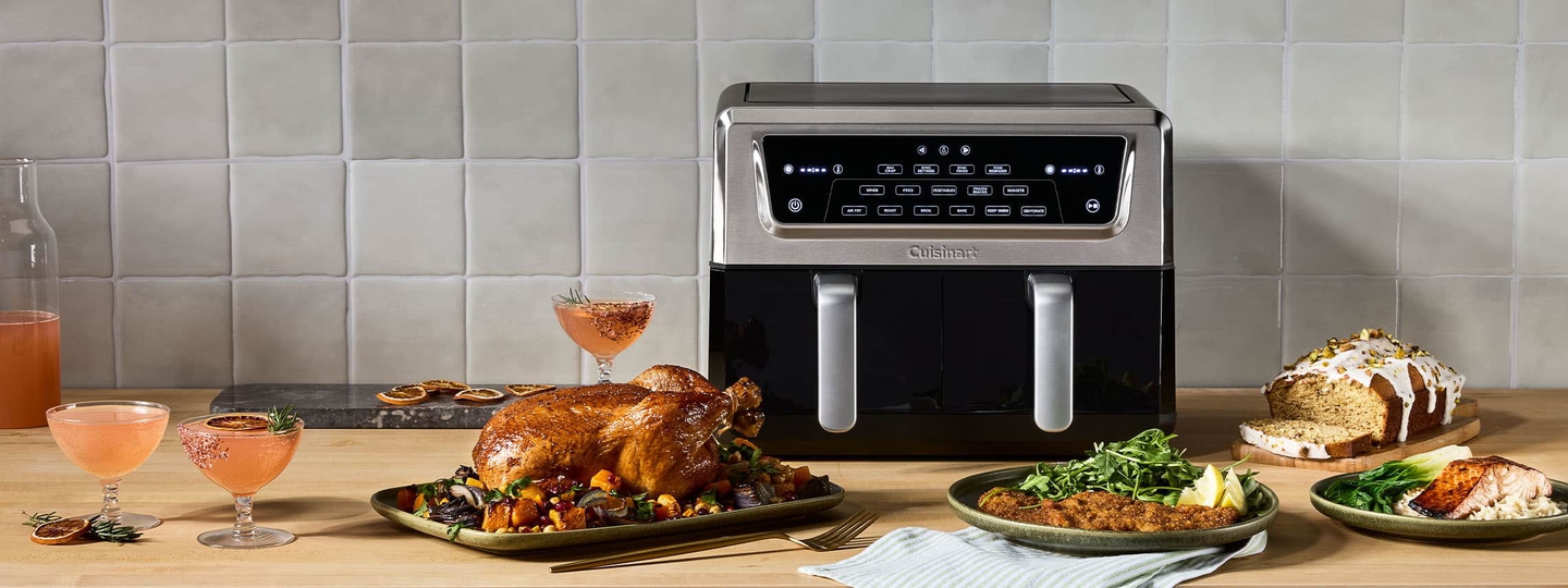 Cuisinart double basket air fryer on countertop with food and drinks.