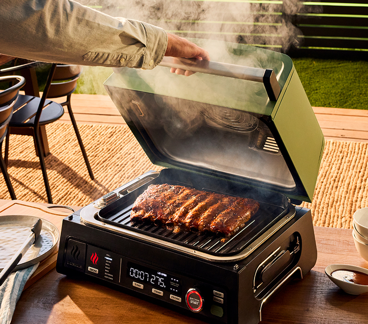 Arm opening lid of electric grill cooking meat with smoke