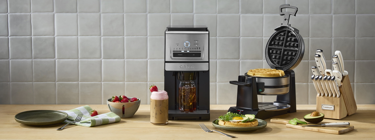 Cuisinart coffee maker, waffle maker, and cutlery on table with food