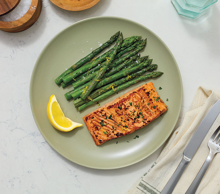 cooked salmon and asparagus with lemon on a green plate