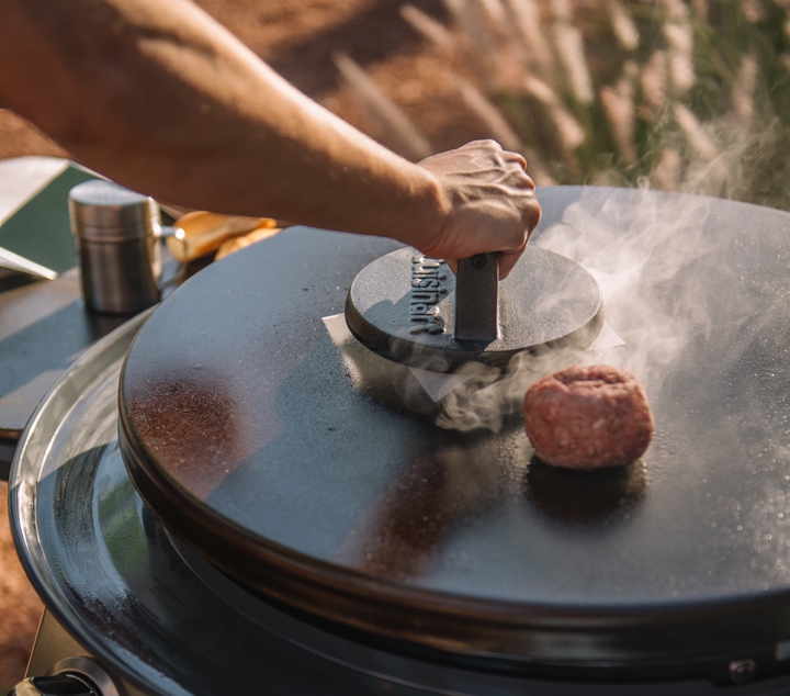 Burger being smashed with cuisinart cast iron burger press