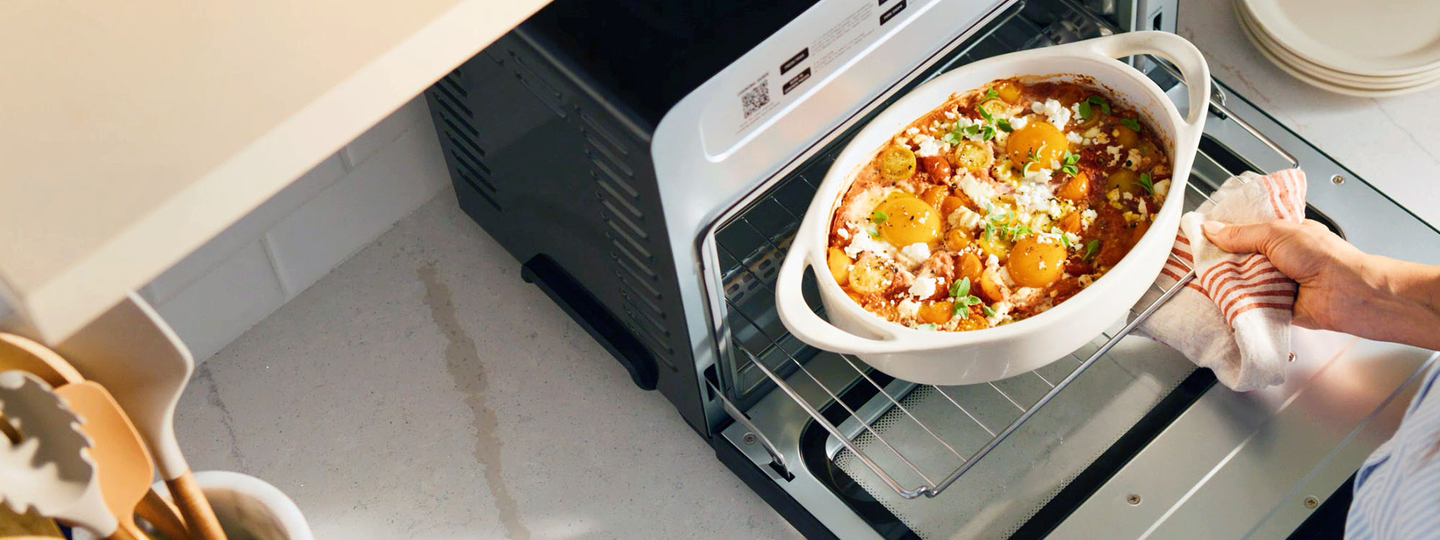 looking down at a Cuisinart Digital Airfryer with door open and a baked dish being pulled out