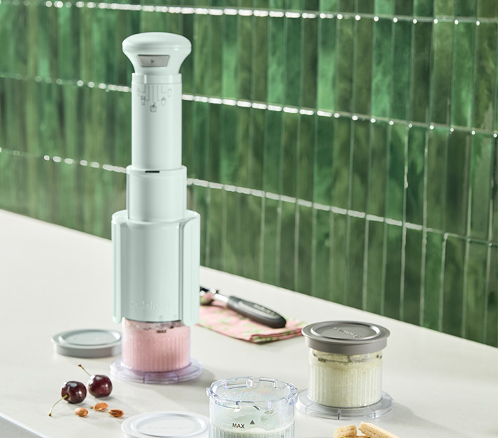 Green ice cream maker with ice cream and ingredients on countertop.