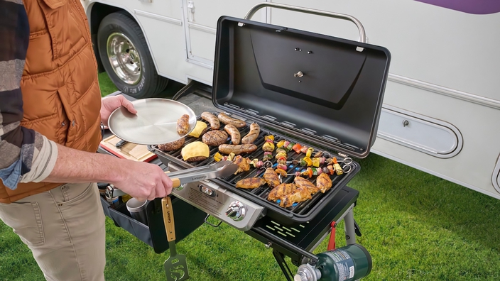 Cuisinart portable grill cooking sausages, chicken, and burgers