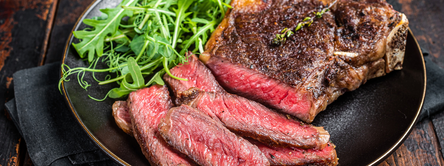 grilled steak on black plate with arugula