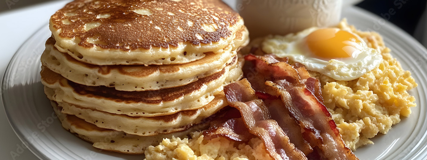 Hearty breakfast with bacon, eggs and pancakes