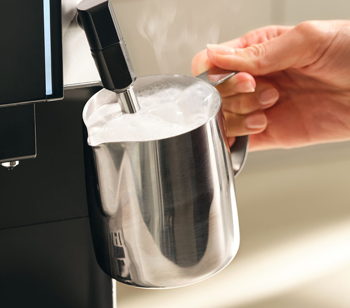 Frothing wand making froth in the stainless steel mug.