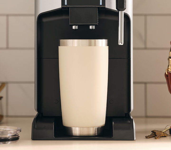 Travel mug in espresso machine for espresso to go.